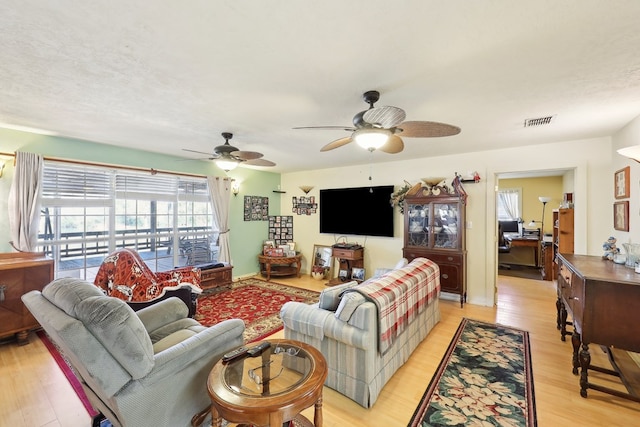 living area featuring a ceiling fan, light wood-type flooring, and visible vents