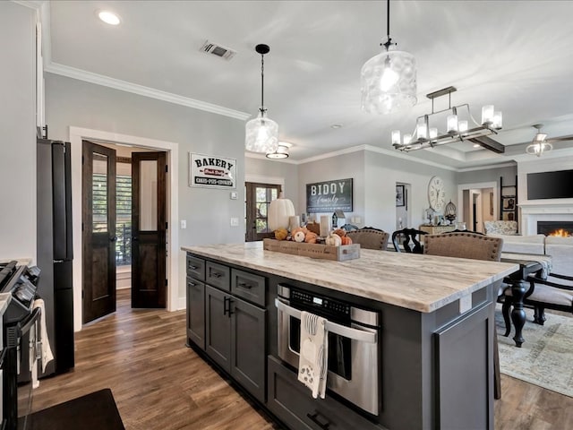 kitchen with light stone countertops, a center island, hanging light fixtures, and dark hardwood / wood-style floors