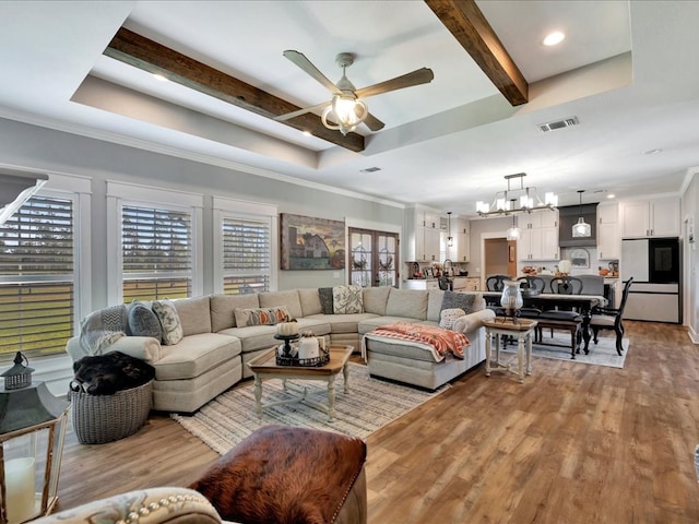 living room with a raised ceiling, ceiling fan with notable chandelier, light hardwood / wood-style flooring, and crown molding