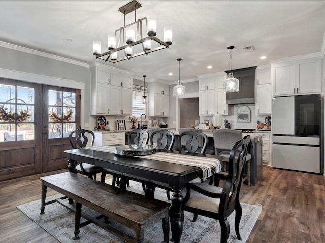 dining room with an inviting chandelier, dark hardwood / wood-style flooring, crown molding, and french doors