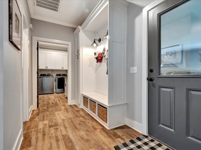 mudroom featuring light wood-type flooring, ornamental molding, and separate washer and dryer