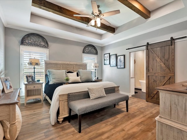 bedroom with hardwood / wood-style floors, ceiling fan, a barn door, and ensuite bathroom