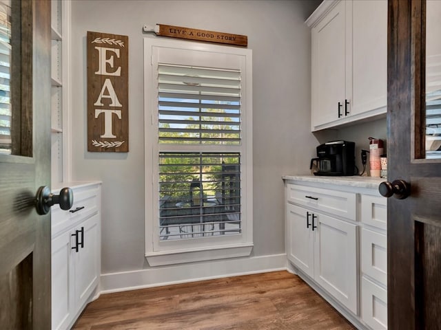 bar featuring hardwood / wood-style floors and white cabinetry