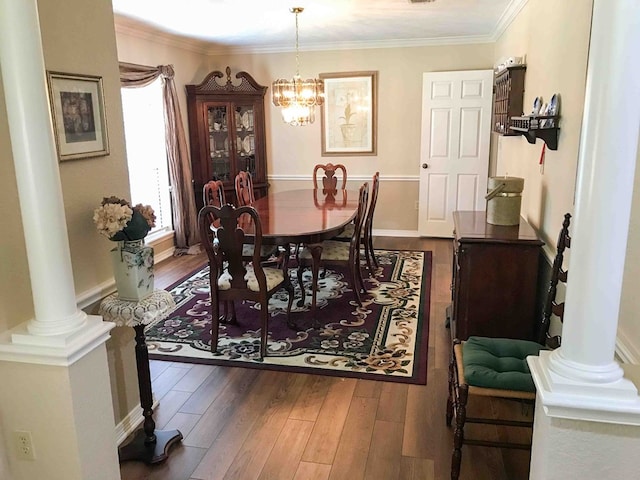 dining room featuring ornate columns, crown molding, hardwood / wood-style floors, and a chandelier