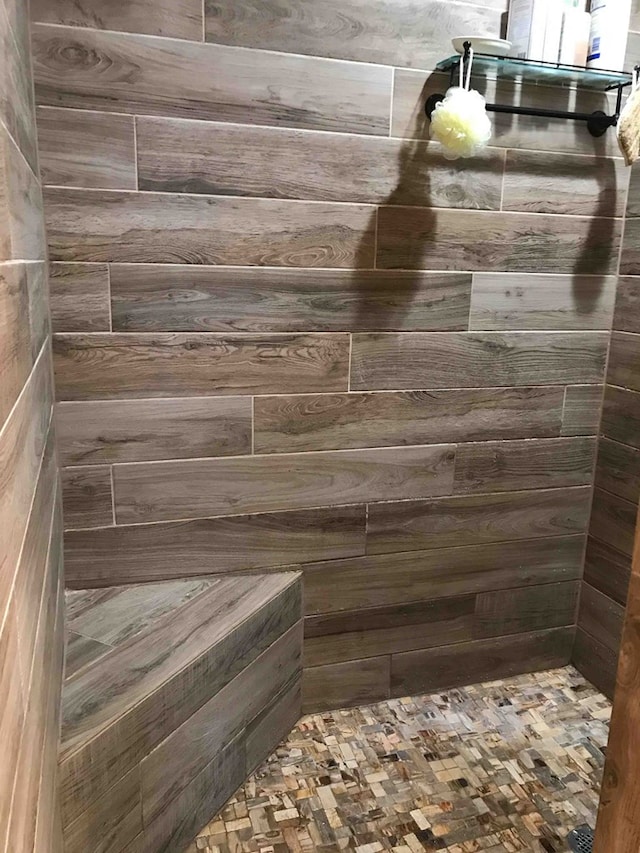 bathroom with a shower and wood walls