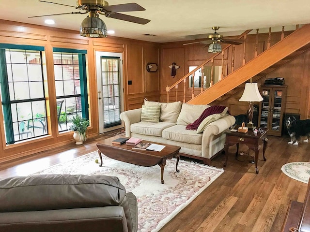 living room featuring ceiling fan, dark wood-type flooring, and wood walls