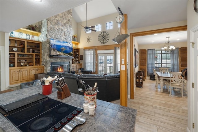 kitchen featuring a stone fireplace, stovetop, light hardwood / wood-style floors, and a healthy amount of sunlight