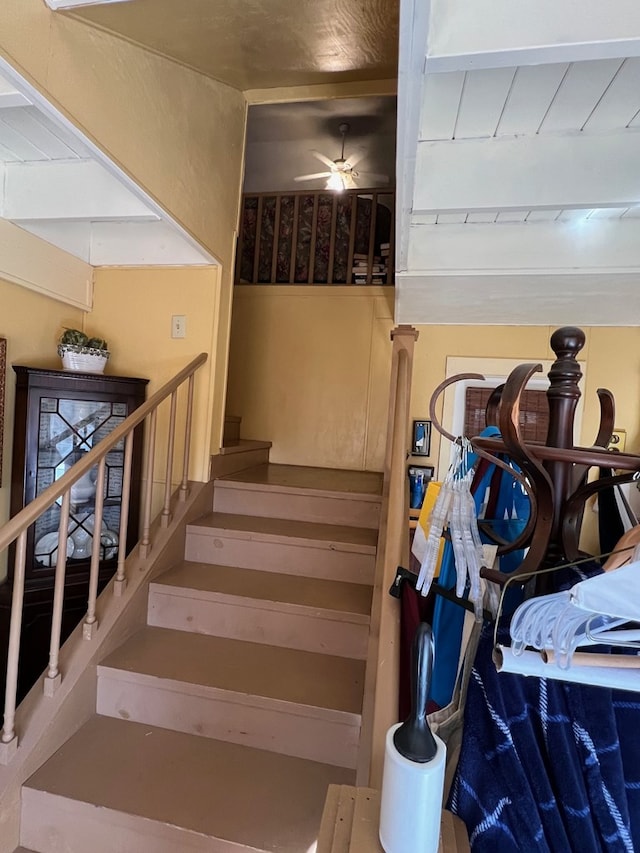 staircase featuring ceiling fan and wooden ceiling