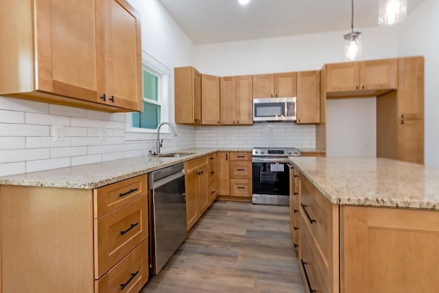 kitchen with light stone countertops, appliances with stainless steel finishes, dark wood-type flooring, sink, and decorative light fixtures