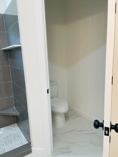 bathroom with a tile shower and toilet