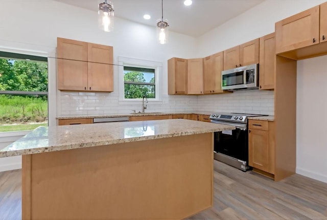 kitchen featuring decorative backsplash, appliances with stainless steel finishes, light wood-type flooring, sink, and pendant lighting