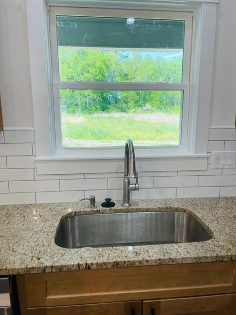 details featuring decorative backsplash, light stone counters, and sink