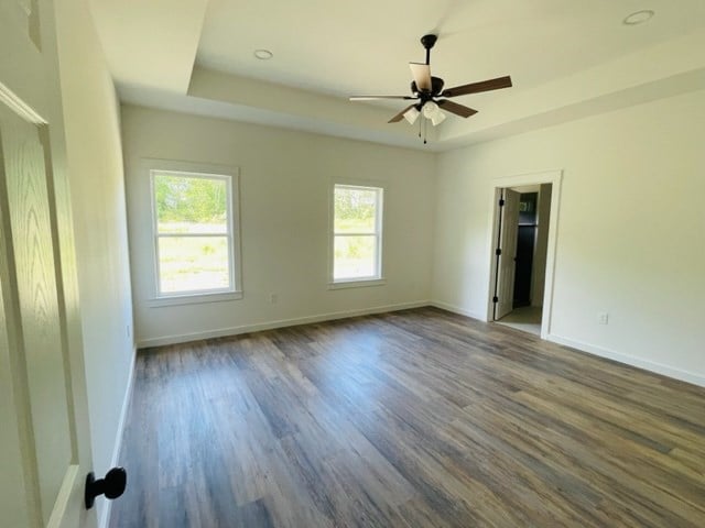 spare room featuring a tray ceiling, ceiling fan, and dark hardwood / wood-style flooring