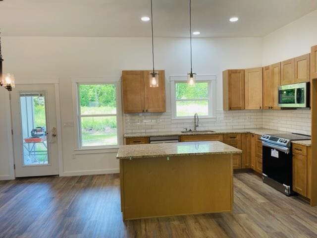 kitchen with appliances with stainless steel finishes, a kitchen island, pendant lighting, and sink