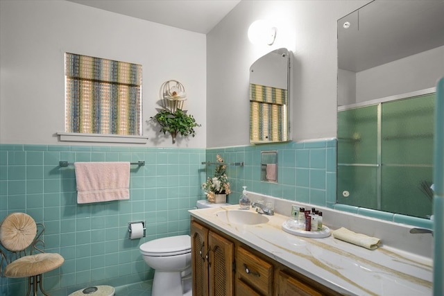 bathroom featuring vanity, toilet, tile walls, and a shower with shower door