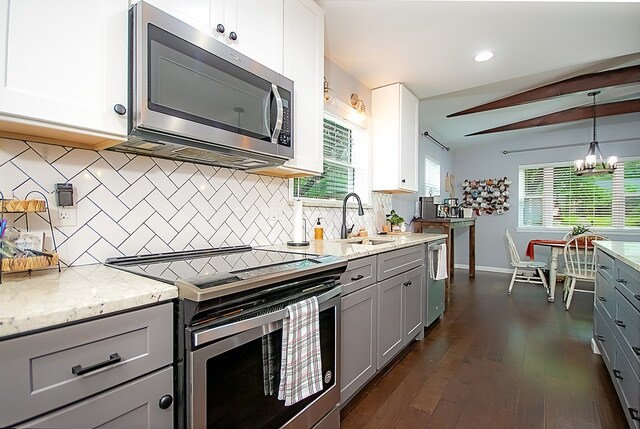 kitchen with sink, hanging light fixtures, stainless steel appliances, dark hardwood / wood-style flooring, and decorative backsplash