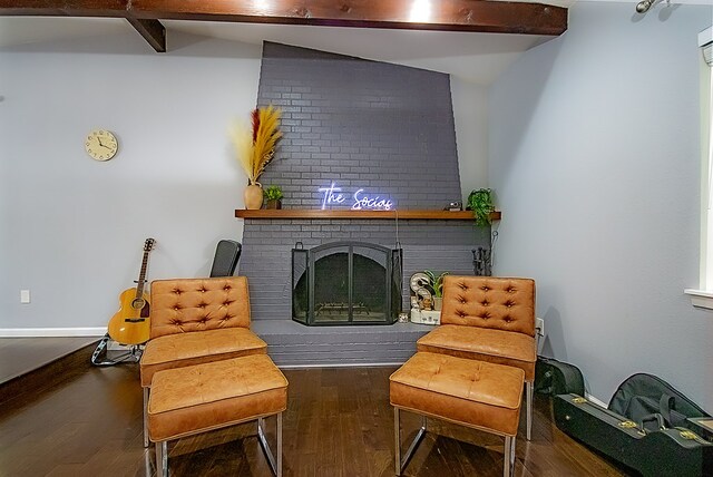 living area with dark hardwood / wood-style flooring, lofted ceiling with beams, and a brick fireplace