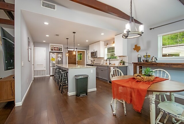 kitchen featuring dark hardwood / wood-style flooring, a kitchen island, stainless steel appliances, and decorative light fixtures