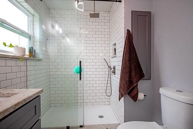 bathroom with a shower with door, vanity, and toilet