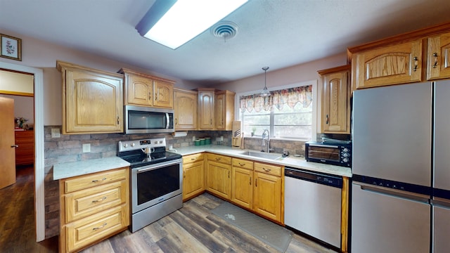 kitchen featuring sink, appliances with stainless steel finishes, tasteful backsplash, decorative light fixtures, and dark hardwood / wood-style flooring