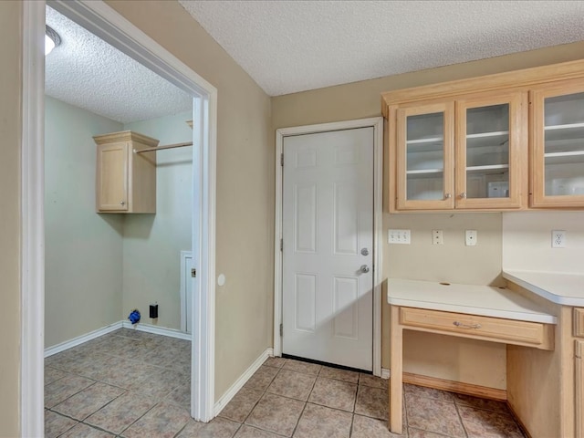 laundry room featuring light tile patterned floors, cabinets, and a textured ceiling