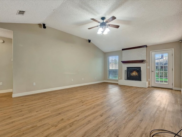 unfurnished living room with a fireplace, light hardwood / wood-style floors, ceiling fan, and lofted ceiling