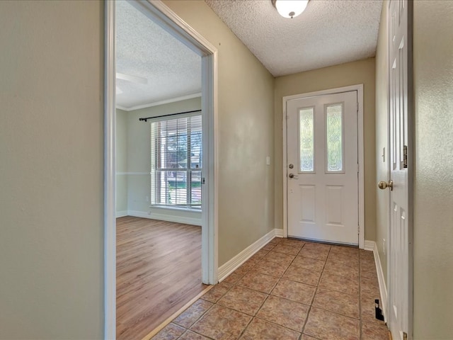 doorway to outside featuring crown molding, light tile patterned floors, and a textured ceiling