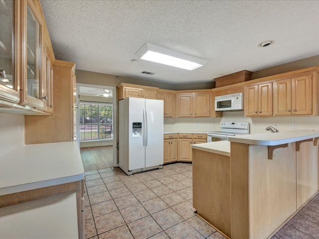 kitchen with kitchen peninsula, a kitchen bar, white appliances, a textured ceiling, and light brown cabinets