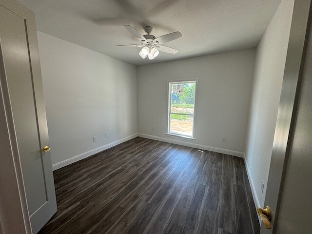 unfurnished living room featuring ornamental molding, a fireplace, dark wood-style floors, a raised ceiling, and a ceiling fan