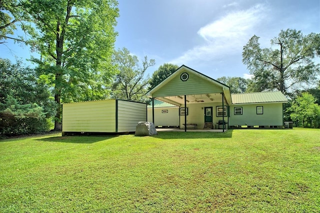 back of house with central air condition unit, ceiling fan, and a lawn