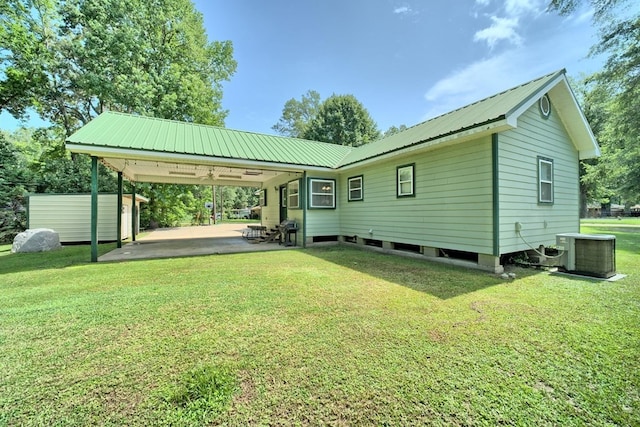 rear view of property with a yard, central AC, and a carport