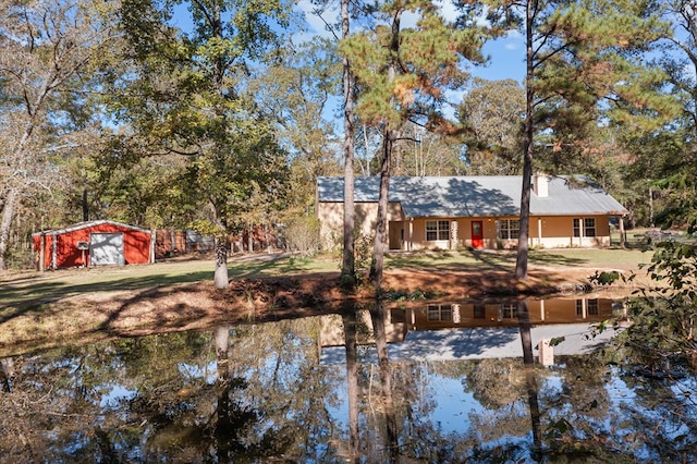 exterior space featuring an outbuilding, a water view, and a lawn