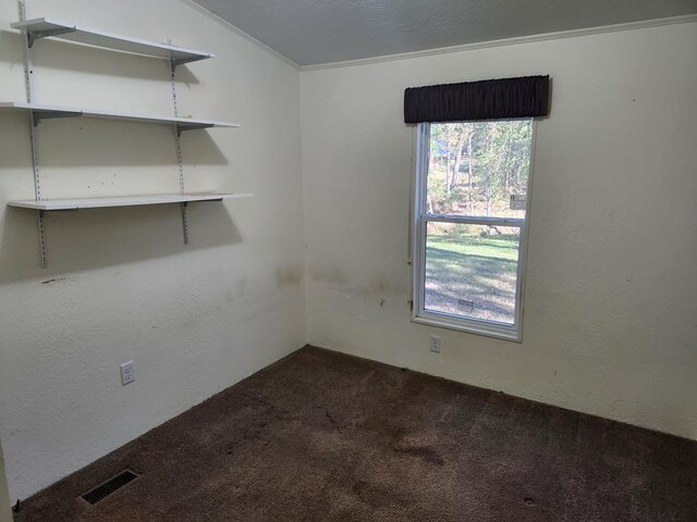 unfurnished room featuring dark colored carpet and ornamental molding