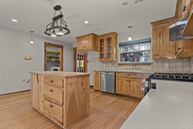 kitchen featuring appliances with stainless steel finishes, backsplash, sink, decorative light fixtures, and light hardwood / wood-style flooring