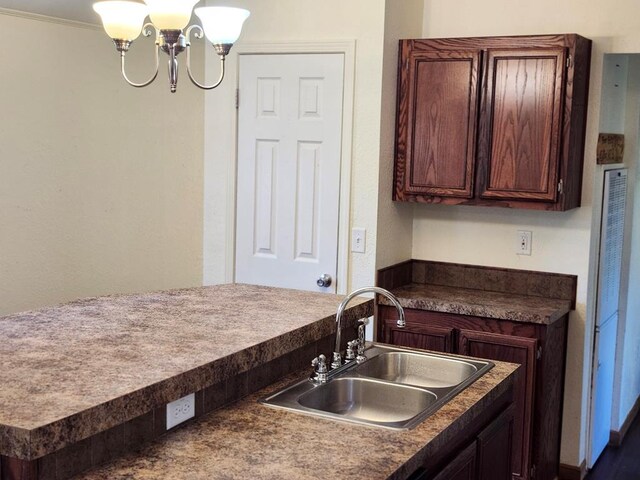 kitchen featuring dark brown cabinets, ornamental molding, sink, and a chandelier