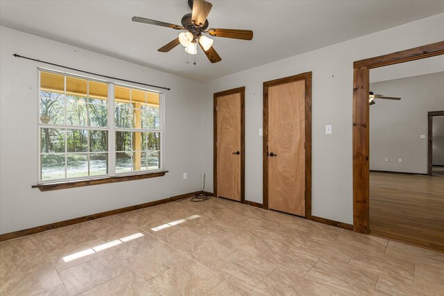 unfurnished bedroom featuring light wood-type flooring, ceiling fan, and multiple closets