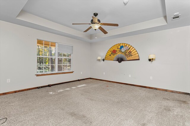 carpeted empty room with a raised ceiling and ceiling fan