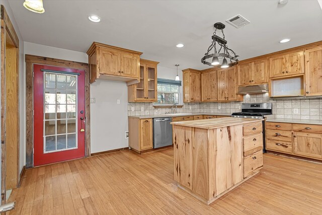 kitchen with tasteful backsplash, hanging light fixtures, stainless steel appliances, and light wood-type flooring