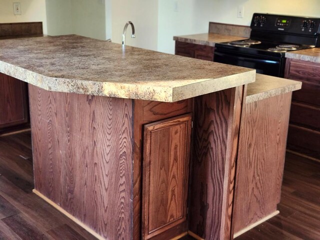 kitchen featuring dark hardwood / wood-style flooring, black electric range, a kitchen island, and sink