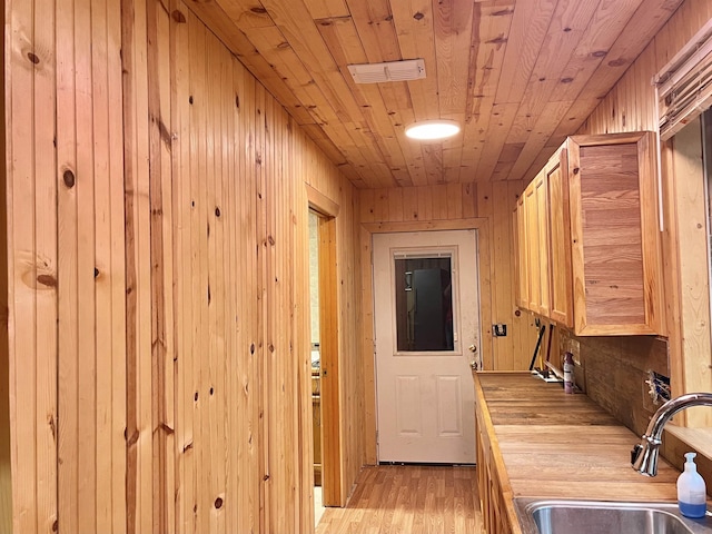 washroom with wood ceiling, sink, wooden walls, and light hardwood / wood-style flooring