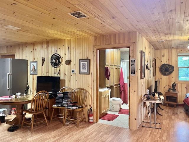 dining space with wooden walls, light hardwood / wood-style floors, and wooden ceiling