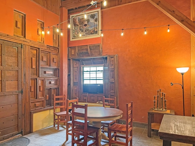 dining area featuring a towering ceiling and light tile patterned floors