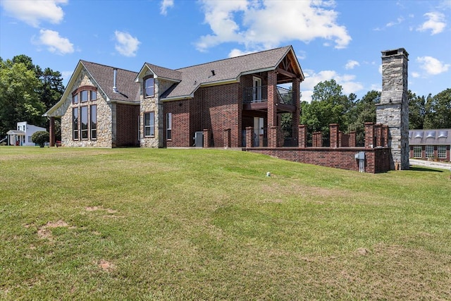 back of house featuring central air condition unit, a balcony, and a lawn