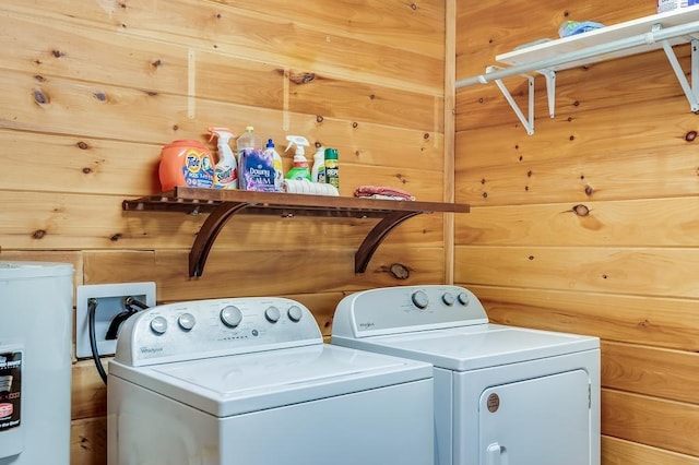 laundry room featuring washer and dryer, wooden walls, and water heater