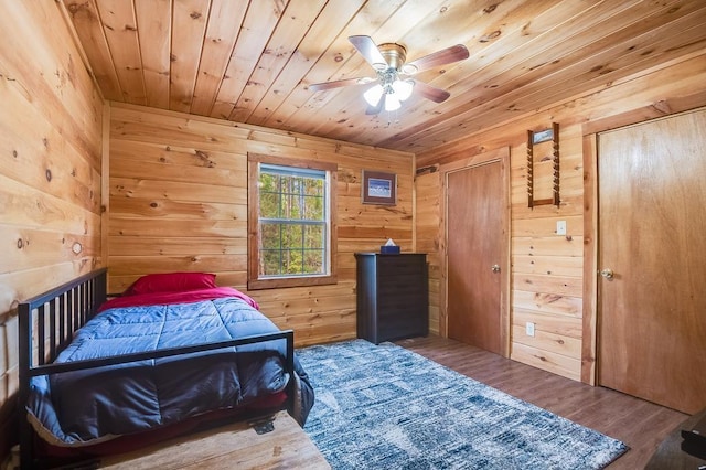 bedroom with wooden walls, ceiling fan, wood ceiling, and hardwood / wood-style flooring