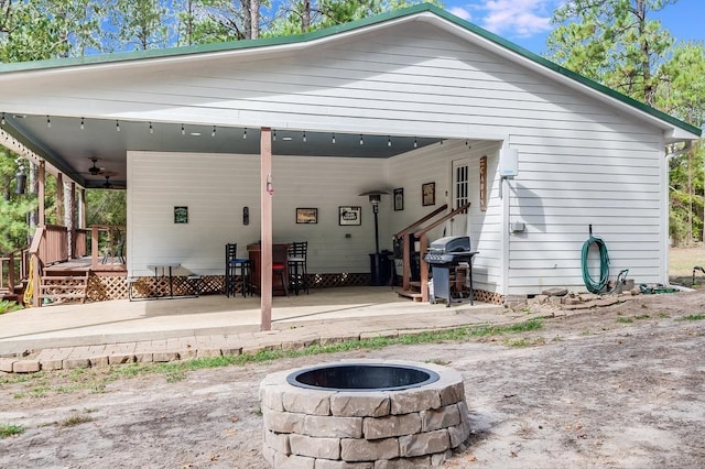 rear view of house with a patio area, ceiling fan, a wooden deck, and a fire pit