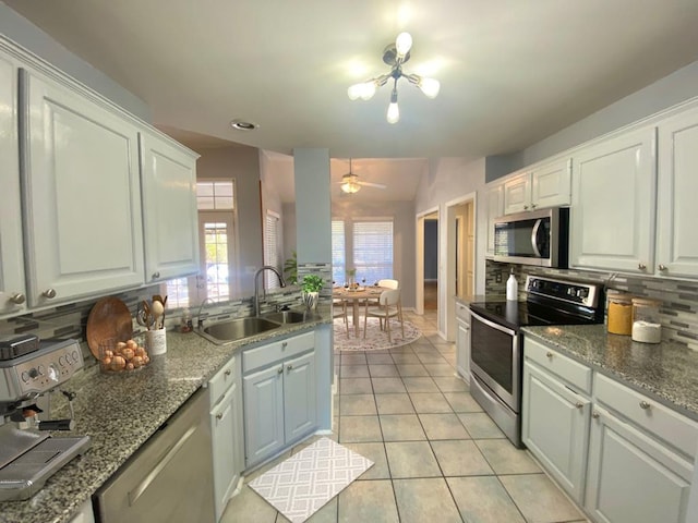 kitchen featuring white cabinetry, vaulted ceiling, decorative backsplash, light tile patterned floors, and appliances with stainless steel finishes