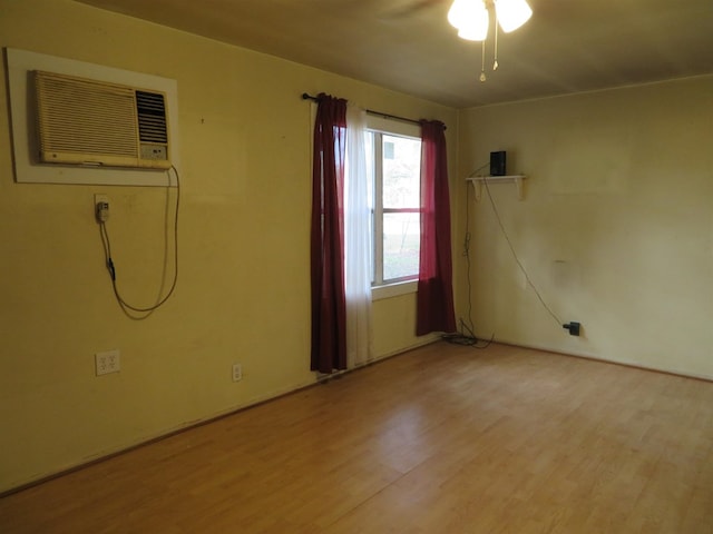 empty room featuring a wall mounted AC and light hardwood / wood-style floors