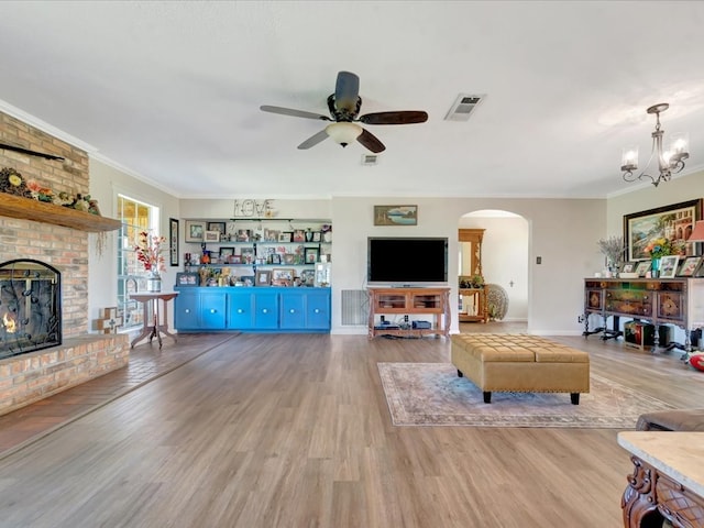 1145 State Highway 21e, San Augustine, TX 75972 - living room with light wood finished floors, arched walkways, ornamental molding, and ceiling fan with notable chandelier