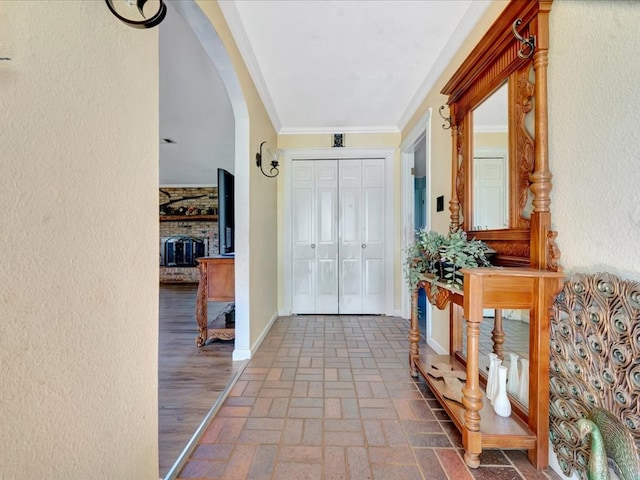 1145 State Highway 21e, San Augustine, TX 75972 - entryway featuring brick floor, arched walkways, a textured wall, a large fireplace, and ornamental molding